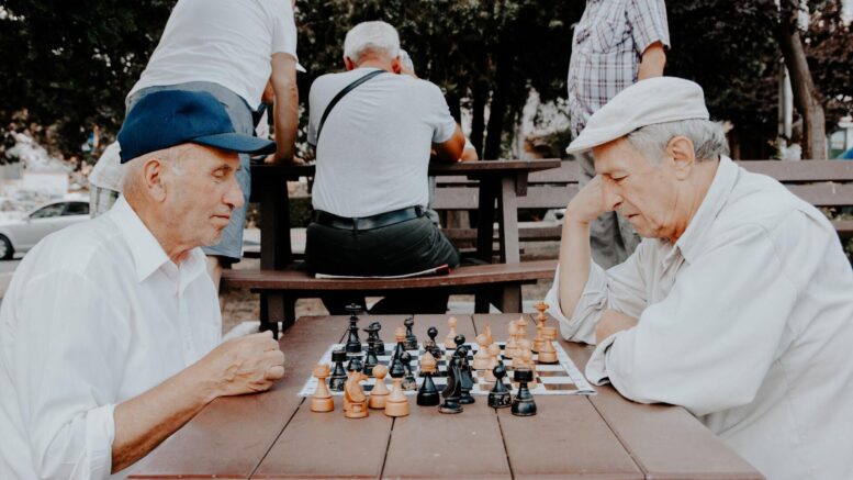 seniorzy grający w szachy w parku